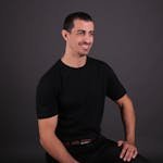 Portrait of a smiling man sitting confidently in a studio setting.